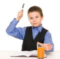 Schoolboy drinks juice at a desk with diary and pen Royalty Free Stock Photo