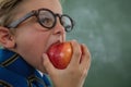 Schoolboy eating red apple against chalkboard Royalty Free Stock Photo