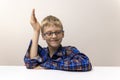 schoolboy with glasses raises his hand. boy in plaid shirt knows answer. Elementary school. Study online from home