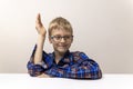 schoolboy with glasses raises his hand. boy in plaid shirt knows answer. Elementary school. Study online from home