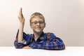 schoolboy with glasses raises his hand. boy in plaid shirt knows answer. Elementary school. Study online from home