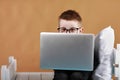 schoolboy in glasses using laptop sitting on bed. Child doing school homework and seriously and tired looking on camera Royalty Free Stock Photo