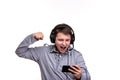 Schoolboy guy with headphones playing on mobile phone. Teenager happy screams . Young man won an online game on a smartphone.