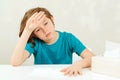 Schoolboy has headache during lessons. Sick boy sitting at the desk. Boy has a virus, runny nose and headache Royalty Free Stock Photo