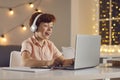 Schoolboy in headphones answers a teacher`s question while sitting at home in front of a laptop.