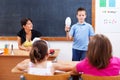 Schoolboy holding bulb in front of class