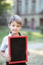 A schoolboy holding a chalk board. Kid holding a black board. Empty space for text. School lessons. Back to school