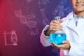 Schoolboy holding Florence flask against blackboard with written chemistry formulas, closeup Royalty Free Stock Photo