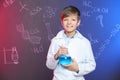 Schoolboy holding Florence flask against blackboard with written chemistry formulas