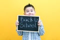 Schoolboy holding a tablet in his hands with the inscription Back to school on a yellow background Royalty Free Stock Photo