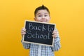 Schoolboy holding a tablet in his hands with the inscription Back to school on a yellow background Royalty Free Stock Photo