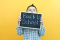 Schoolboy holding a tablet in his hands with the inscription Back to school on a yellow background Royalty Free Stock Photo
