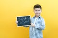 Schoolboy holding a tablet in his hands with the inscription Back to school on a yellow background Royalty Free Stock Photo