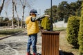 Schoolboy kid throwing the trash into dumpster. Boy using recycling bin to throw away the litter. Caucasian child Royalty Free Stock Photo