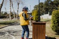Schoolboy kid throwing the trash into dumpster. Boy using recycling bin to throw away the litter. Caucasian child Royalty Free Stock Photo