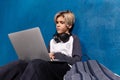 Schoolboy with laptop and wireless headphones doing homework sitting on floor