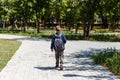 A schoolboy with a large backpack on his back walks along a path in the park