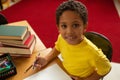 Schoolboy looking at camera while studying at desk in a classroom