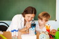 Schoolboy looking inot microscope while the biology teacher is attending him Back to school concept.