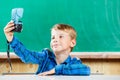 Schoolboy make selfie at blackboard in school
