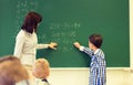 Schoolboy with math teacher writing on chalk board Royalty Free Stock Photo