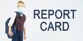 A schoolboy with a medical mask on his face is holding a school backpack, next to it is written the text - REPORT CARD Royalty Free Stock Photo