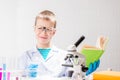 A schoolboy with a microscope and book examines chemicals in test tubes, conducts experiments - a portrait