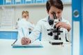 Schoolboy with microscope and copybook in science laboratory Royalty Free Stock Photo