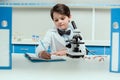 Schoolboy with microscope and copybook in science laboratory Royalty Free Stock Photo