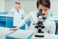 Schoolboy with microscope and copybook in science laboratory Royalty Free Stock Photo