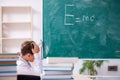 Schoolboy physicist in front of green board Royalty Free Stock Photo