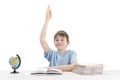 Schoolboy raised his hand during the lesson. Excellent student knows the answer. Portrait of boy at table next to notebooks and