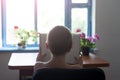 Schoolboy reading a book with interest. Home interior. Back view Royalty Free Stock Photo