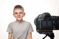 Schoolboy is ready to give the interview on a camcorder. Young video blogger. White background