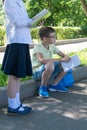 Schoolboy reflected with a book in his hands, a girl reads a book at an outdoor lesson Royalty Free Stock Photo