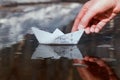 The schoolboy`s hand launches a small paper boat made of a schoo