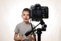 Schoolboy is saying something on a camcorder. Young video blogger. White background