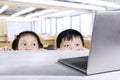 Schoolboy and schoolgirl peeping laptop in classroom Royalty Free Stock Photo