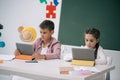 Schoolboy and schoolgirl using digital tablets while sitting at desk in classroom Royalty Free Stock Photo