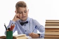 A schoolboy in a shirt is sitting at a table with books and doing homework. Distance learning Royalty Free Stock Photo