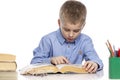 The schoolboy sits at the table and does his homework. Isolated on a white background