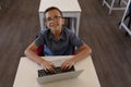 Schoolboy sitting at a desk using a laptop computer in an elementary school classroom Royalty Free Stock Photo