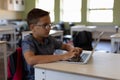 Schoolboy sitting at a desk using a laptop computer in an elementary school classroom Royalty Free Stock Photo