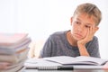 Schoolboy sitting among pile of books, textbooks, school exercise books on his desk and doing homework. Education Royalty Free Stock Photo