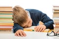 schoolboy is sleeping at a table between piles of books on a white background Royalty Free Stock Photo