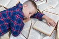 The schoolboy sleeps on a pile of open books. Learning difficulties. Top view Royalty Free Stock Photo
