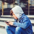 Schoolboy with smartphone sitting on stairs after school. Technology, education and lifestyle concept. Kid texting message or Royalty Free Stock Photo