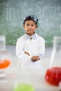 Schoolboy standing in classroom with chemical flask in foreground Royalty Free Stock Photo