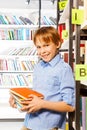 Schoolboy stands and holds books in library