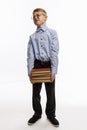 A schoolboy stands and holds a heavy pile of books in his hands. White background. Vertical